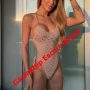 Woman in a beige crochet one-piece swimsuit posing in front of a glass door, with red diagonal text 'Gaziantep Escort Bayan' across her torso. Woman in a beige crochet one-piece swimsuit posing in front of a glass door, with red diagonal text 'Gaziantep Escort Bayan' across her torso.